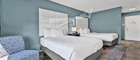 Una habitación de hotel moderna con una cama grande, dos mesitas de noche, una silla y una puerta.