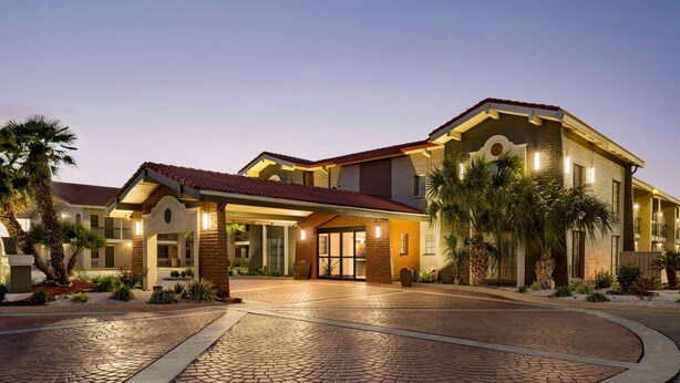 A large, two-story building with a red-tiled roof and a covered entrance. - La Quinta Inn by Wyndham Victoria (Victoria)