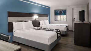 A hotel room with two beds, a desk, a TV, and a painting on the wall. - La Quinta Inn by Wyndham Victoria (Victoria)