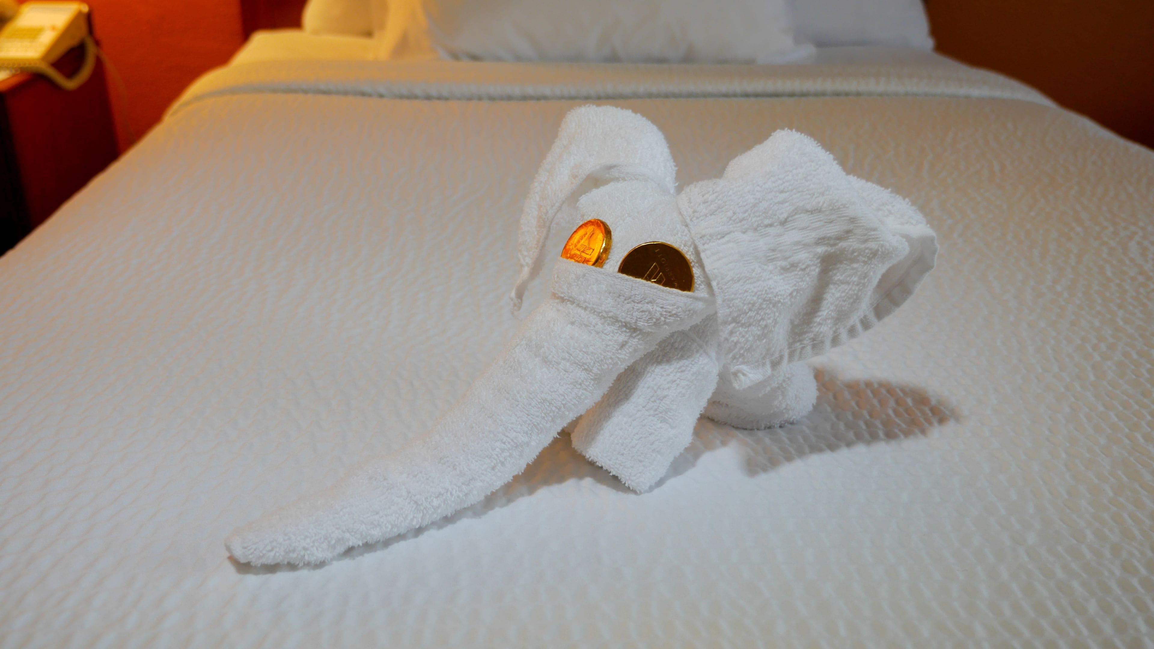 A white towel with a plush elephant head on a bed.