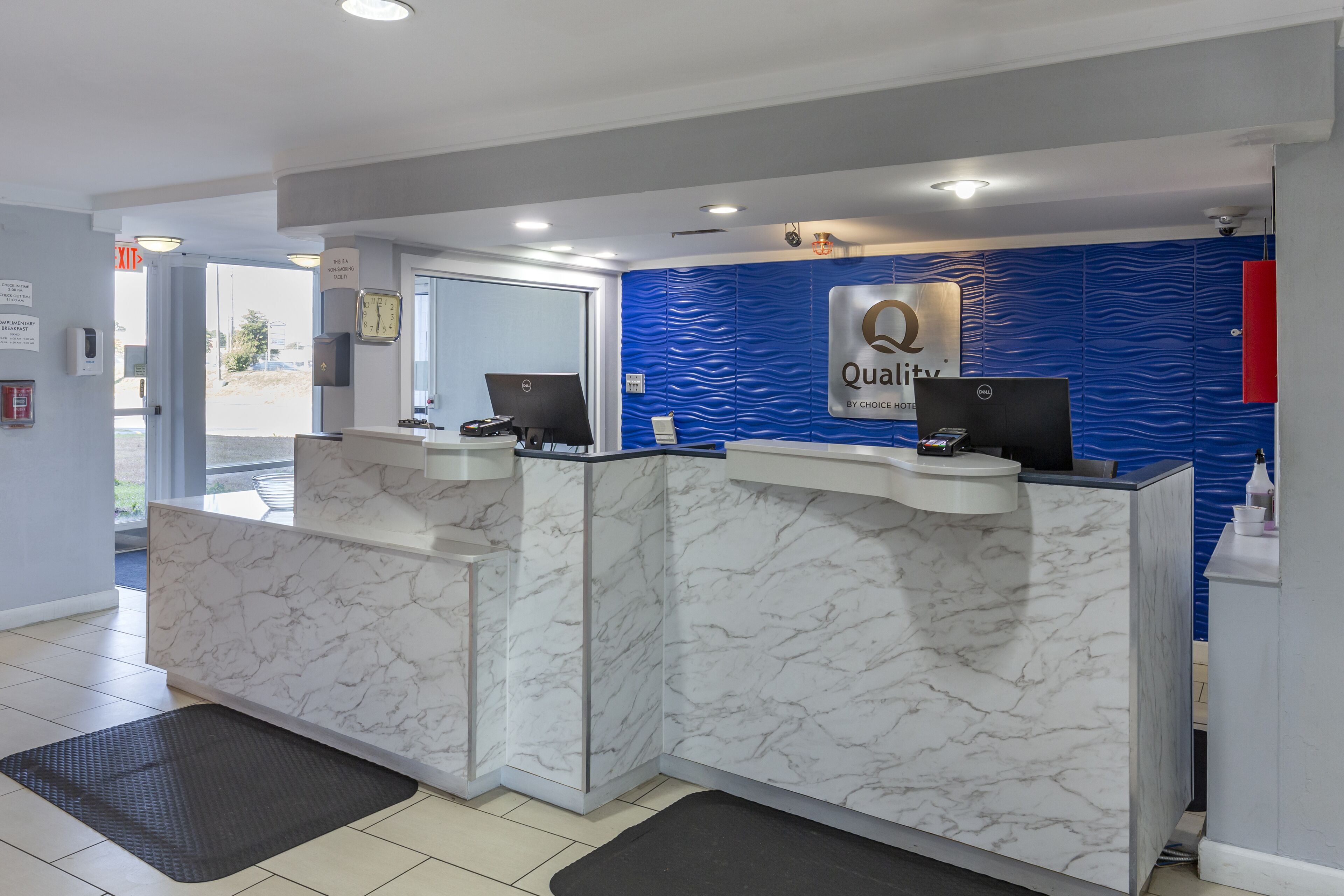 A hotel reception area with marble counters, a blue textured wall, and a sign that reads "Quality by Choice Hotels."
