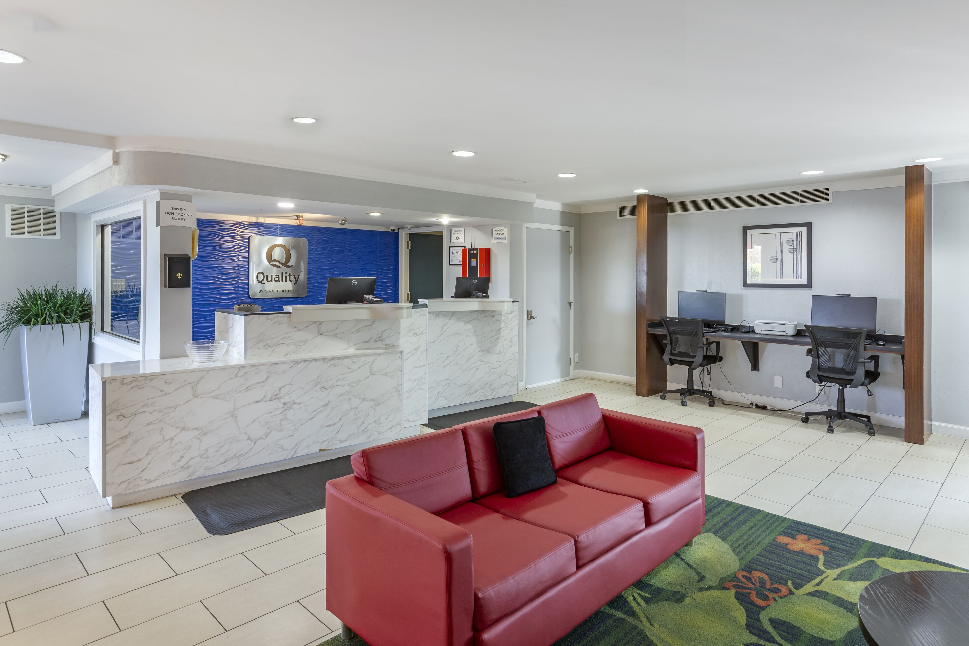 A reception area with a marble counter, a red leather sofa, and a desk with computers.
