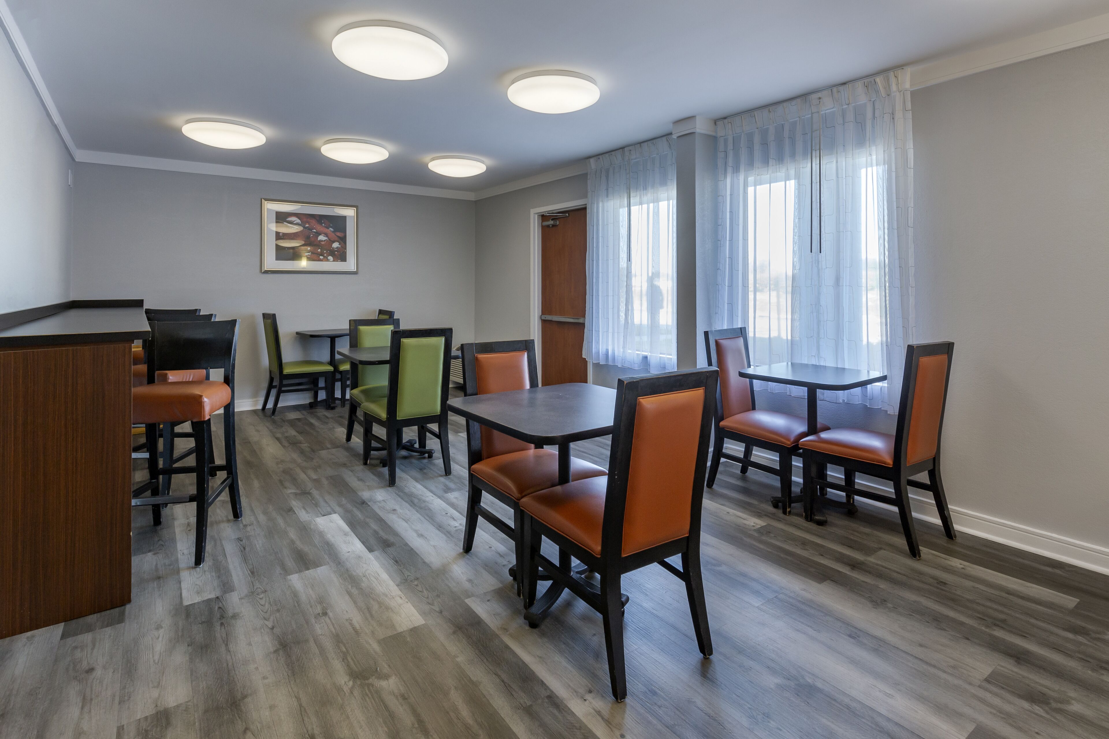 Un comedor con suelo de madera, varias mesas y sillas, y una barra.