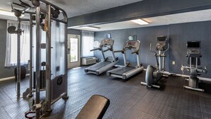 Un gimnasio con cintas de correr, elípticas y equipo de levantamiento de pesas.