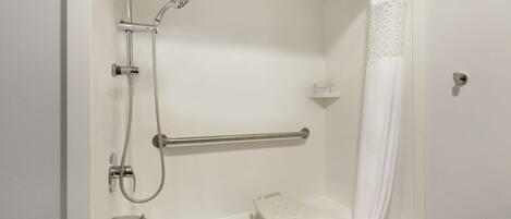 A bathroom with a shower, grab bar, and a wheelchair-accessible bench.