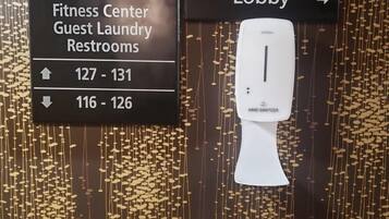 A directional sign for guest restrooms and a hand sanitizer dispenser in a lobby area.