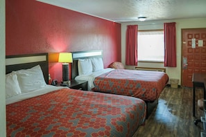 Una habitación de hotel con dos camas, una mesita de noche, una lámpara y una ventana con cortinas.
