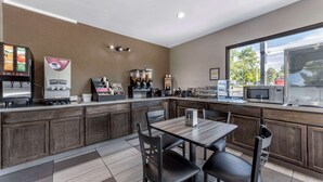 Eine moderne Küchenzeile mit Kaffeemaschine, Mikrowelle und einem Esstisch mit Stühlen.