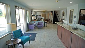 A modern kitchen with a dining area, a bar, and a staircase leading to another level. - Baymont | Monte Vista (Monte Vista)