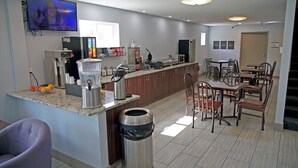 A modern kitchen with a coffee machine, microwave, and a TV mounted on the wall.