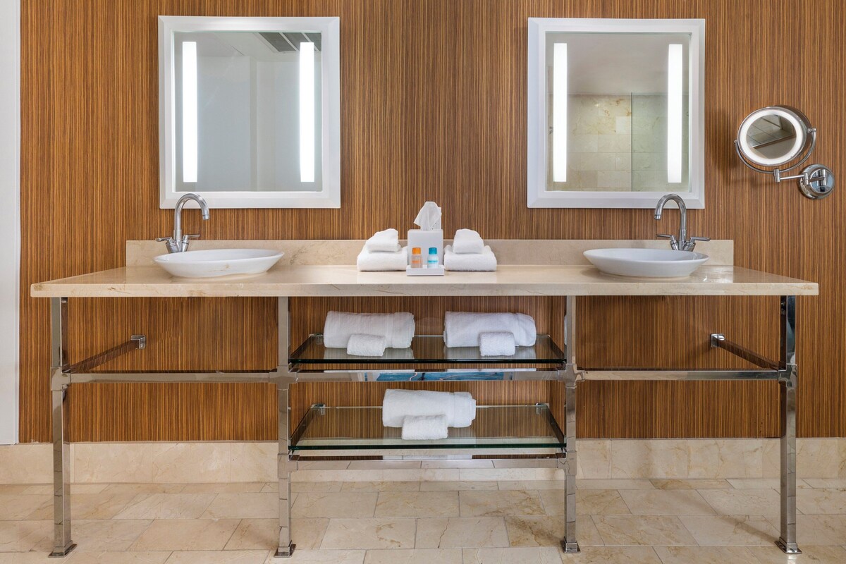 Un baño moderno con dos lavamanos, espejos y un perchero para toallas.