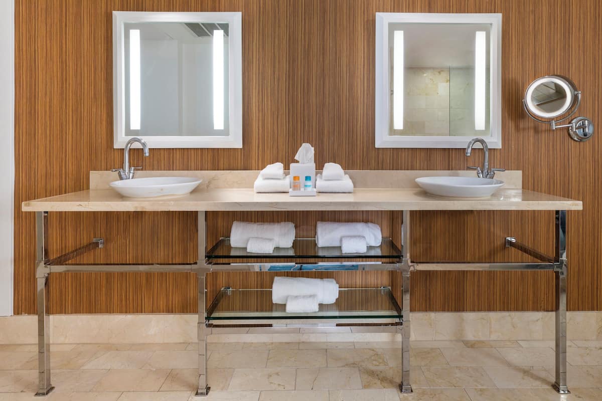 Un baño moderno con dos lavamanos, espejos y un perchero para toallas.