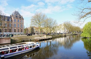 A canal with a boat, a bridge, and a historic building. - Leonardo Hotel Amsterdam Museum Quarter (Amsterdam)