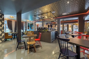 Een moderne barruimte met een toonbank, krukken en een gestreept plafond.