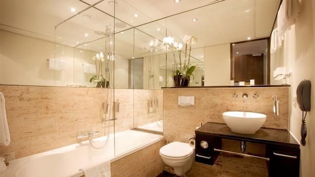 Un baño moderno con ducha de vidrio, bañera independiente, inodoro y tocador con lavamanos.