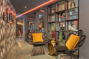 Un intérieur moderne avec des chaises en osier, un mur à motifs et un coin bar doté d’étagères.