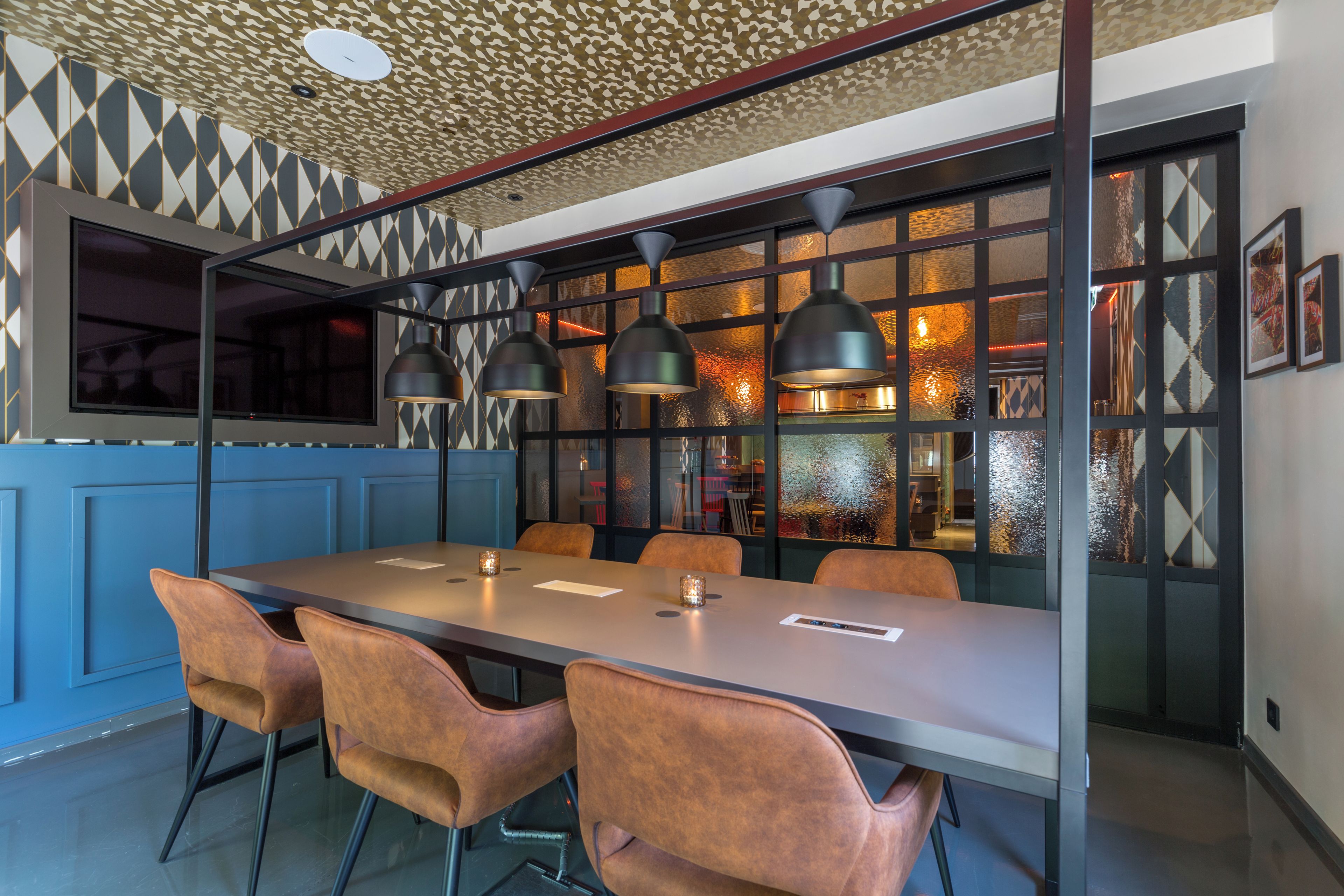 Un comedor moderno con una mesa larga, varias sillas, iluminación colgante y un techo con diseño.