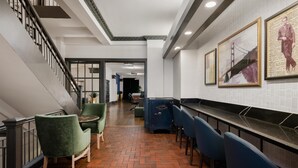 A hotel lobby with a staircase, green chairs, a bar area, and framed artwork on the wall. - The Cartwright Hotel - Union Square BW Premier Collection (San Francisco)
