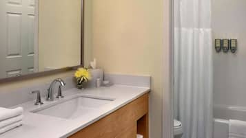 A bathroom with a sink, mirror, and shower area.