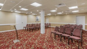 A conference room with a red carpet, white pillars, and rows of chairs.
