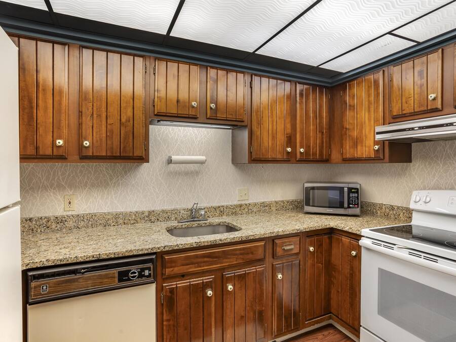 A kitchen with wooden cabinets, a granite countertop, a built-in microwave, and a dishwasher.
