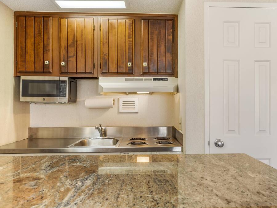Una cocina con armarios de madera, microondas, estufa y encimera de granito.