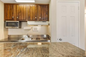 A kitchen with wooden cabinets, a microwave, a stove, and a granite countertop.