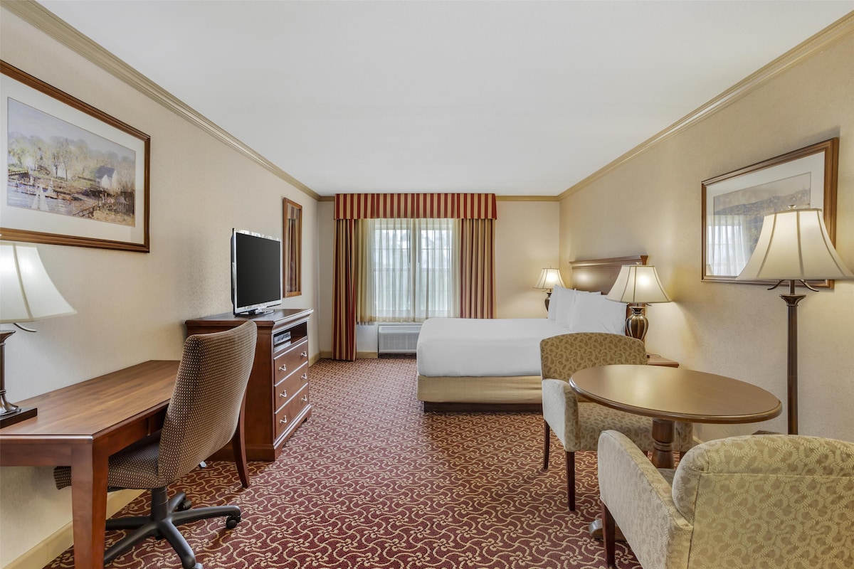 Une chambre d’hôtel équipée d’un lit, d’un bureau, d’une chaise, d’une télévision et de deux lampes.