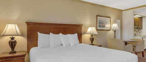 A hotel room with a large bed, two bedside tables with lamps, a chair, and a small table.