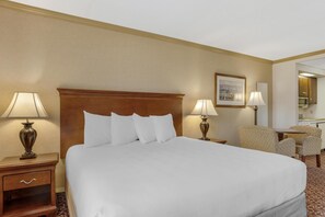 A hotel room with a large bed, two bedside tables with lamps, a chair, and a small table. - Best Western PLUS Morristown Inn-Florham Park (Morristown)