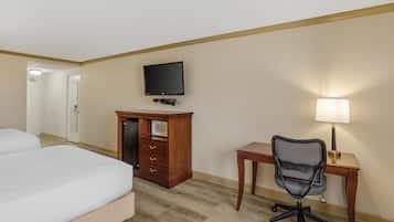 Una habitación de hotel con cama, escritorio con lámpara, televisor y armario.