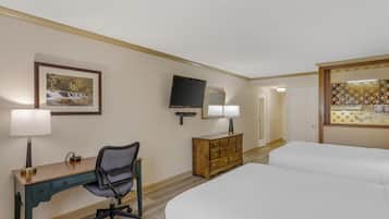 A hotel room with a bed, a desk with a chair, a dresser, a television, and a framed picture on the wall.