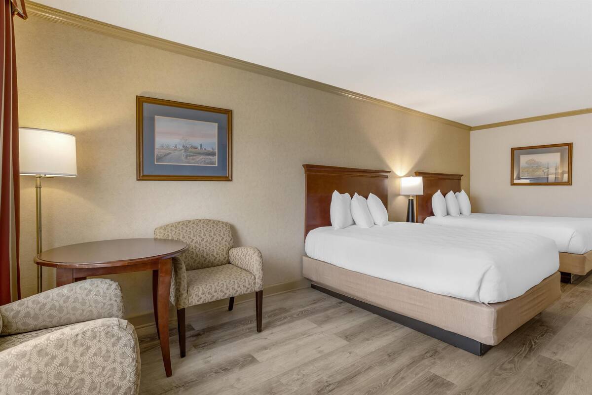 A hotel room with a large bed, two bedside tables, a chair, and a small table.