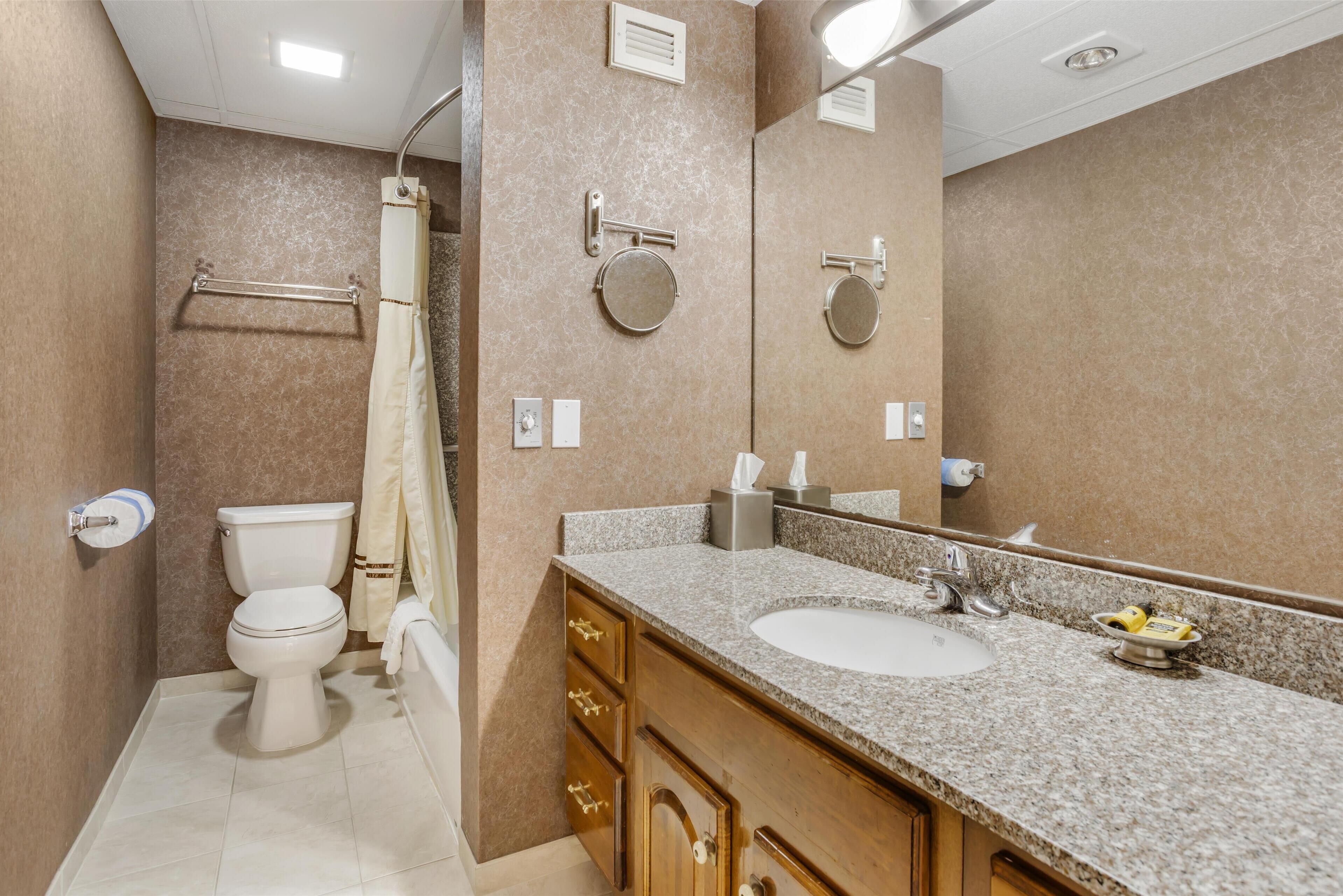 A bathroom with a toilet, sink, mirror, towel rack, and shower curtain.