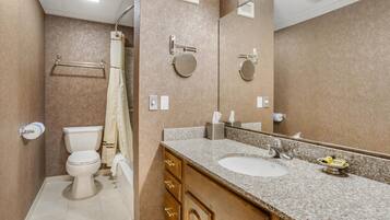 A bathroom with a toilet, sink, mirror, towel rack, and shower curtain.