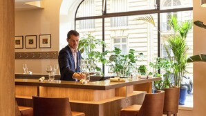 A bar area with a bartender, wooden bar counter, and several chairs. - Sofitel Paris Arc de Triomphe (Paris)