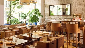 A restaurant with wooden furniture, multiple dining tables, and potted plants. - Sofitel Paris Arc de Triomphe (Paris)