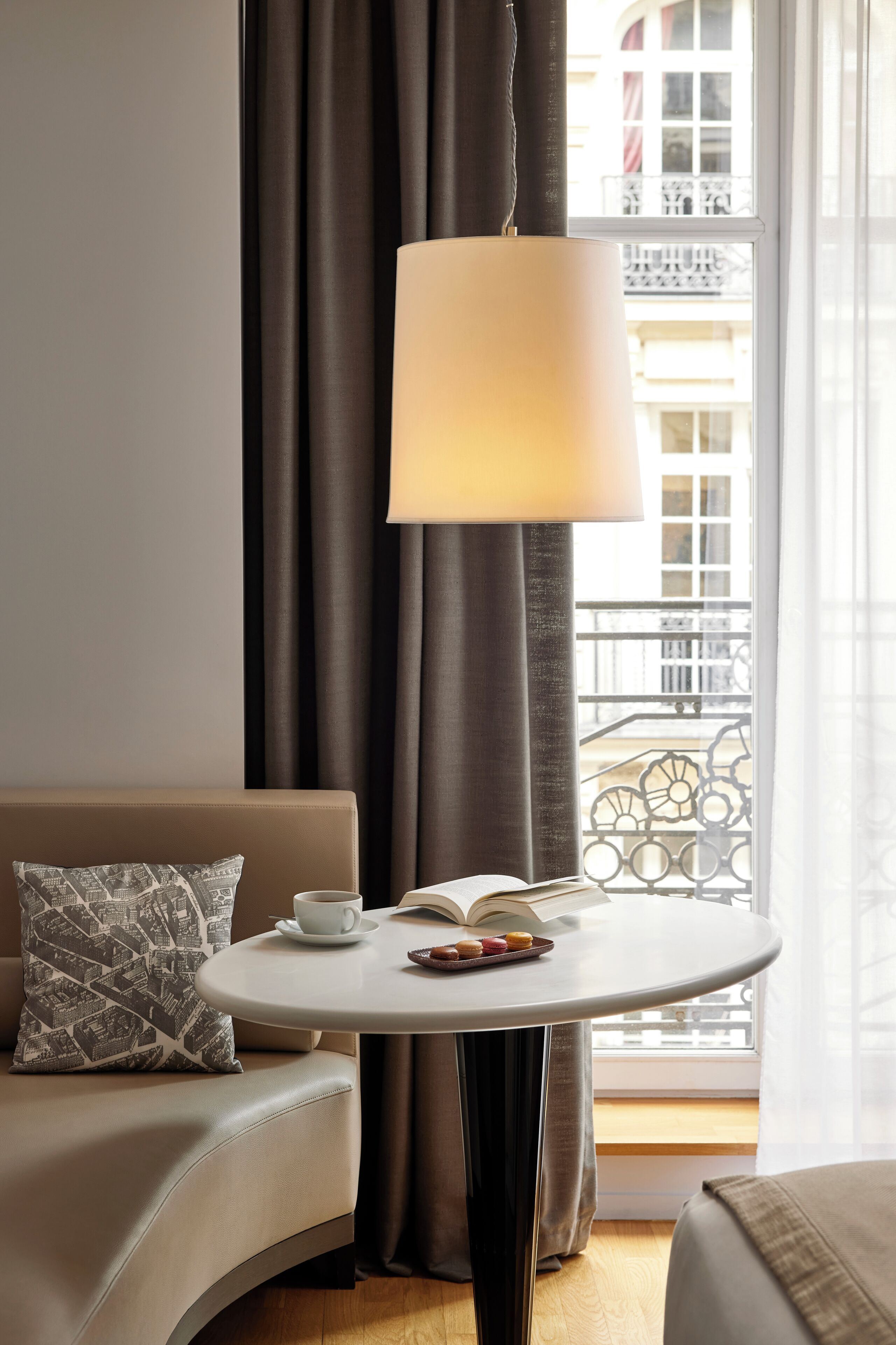 A cozy room with a round table, a sofa, a lamp, and a view of a balcony.