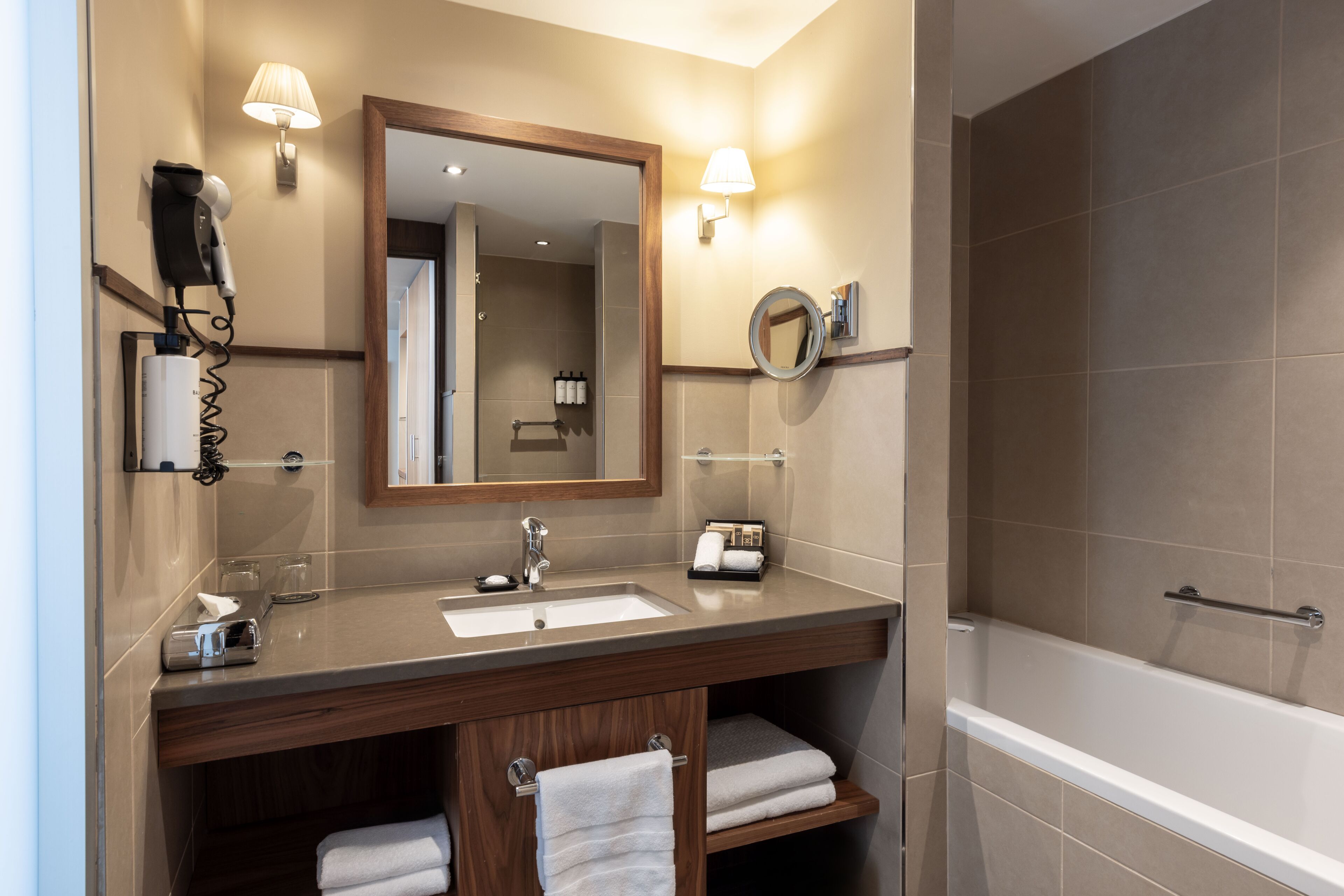 A bathroom with a sink, mirror, towel rack, and a shower area.