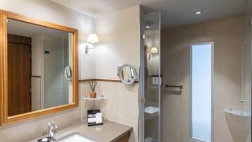 A modern bathroom with a large mirror, a sink, a glass shower enclosure, and a towel rack.