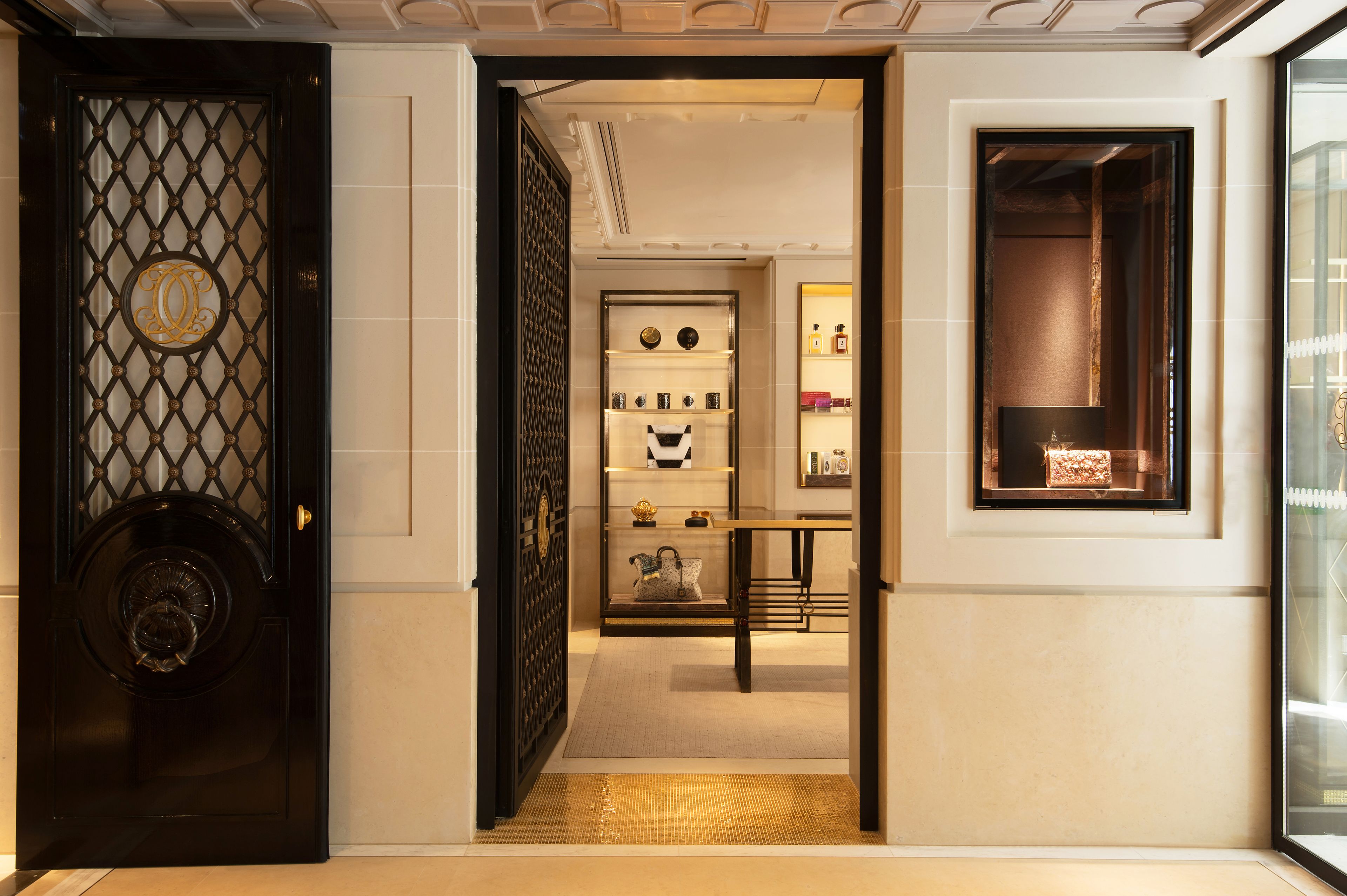 Un hall d’hôtel avec une porte noire richement décorée, un comptoir d’accueil et une vitrine exposant divers objets.