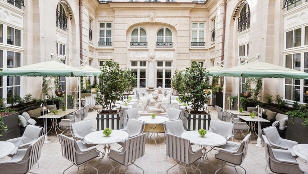 A courtyard with outdoor seating, a fountain, and a building facade with arched windows and balconies. - Hôtel de Crillon A Rosewood Hotel (Paris)