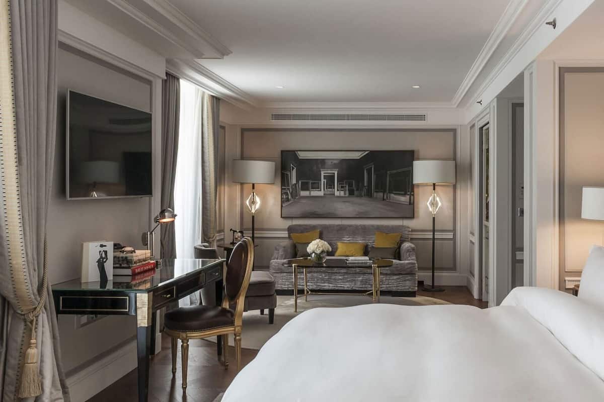 Une chambre d’hôtel avec un grand lit, un bureau, une chaise, un canapé et une télévision.
