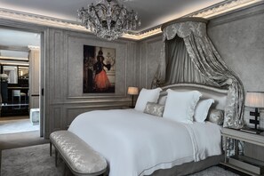 A luxurious bedroom with a large bed, ornate canopy, and a chandelier.