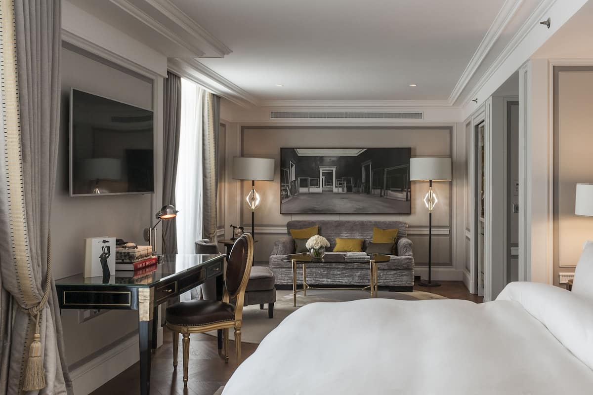 Une chambre d’hôtel avec un grand lit, un bureau avec une chaise, un canapé et deux lampes.