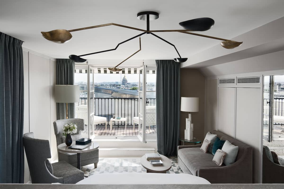 Une chambre d’hôtel moderne dotée d’un balcon, d’un grand lit, d’un canapé et d’un coin repas.