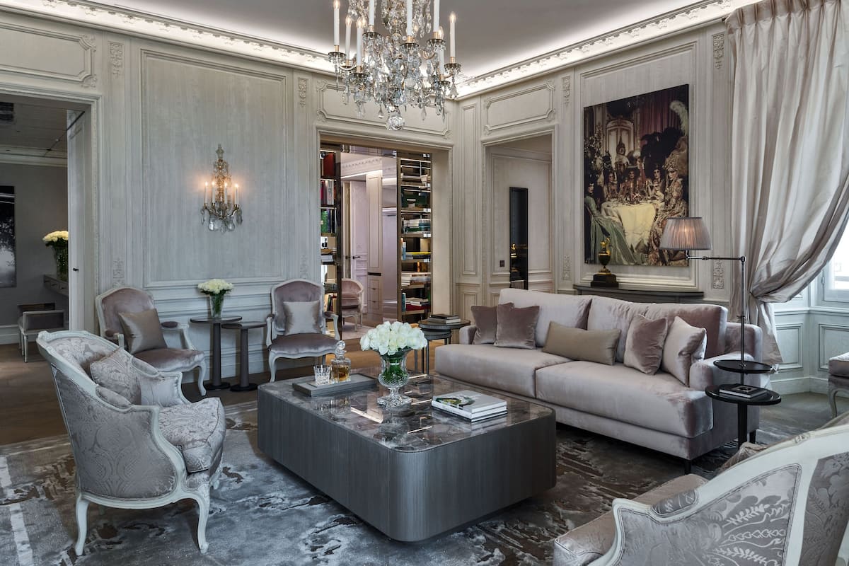 Un salon luxueux, agrémenté d’un grand lustre, de meubles élégants et d’un tableau imposant accroché au mur.