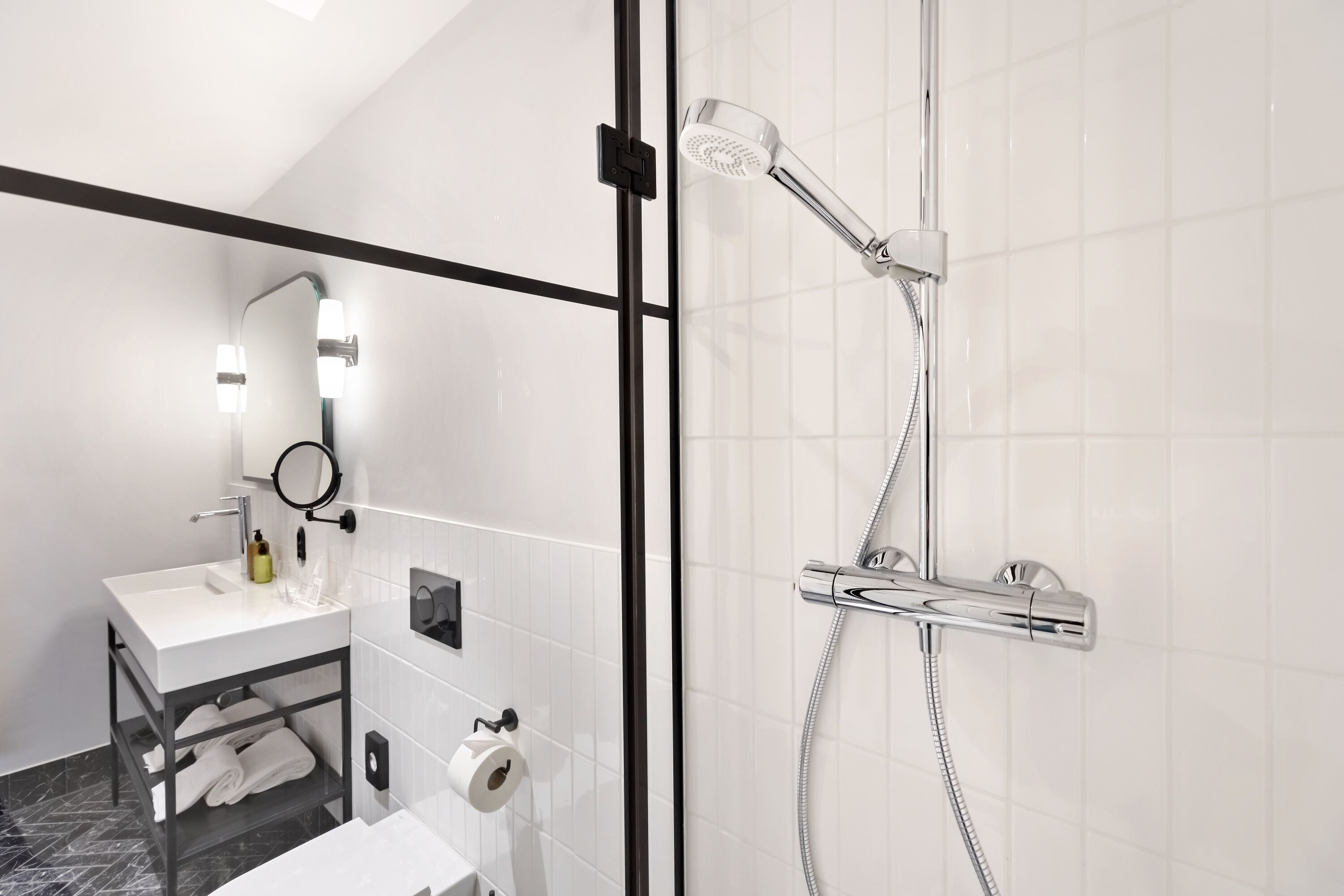 A modern bathroom with a glass-enclosed shower, a white sink, and a vanity with a mirror.