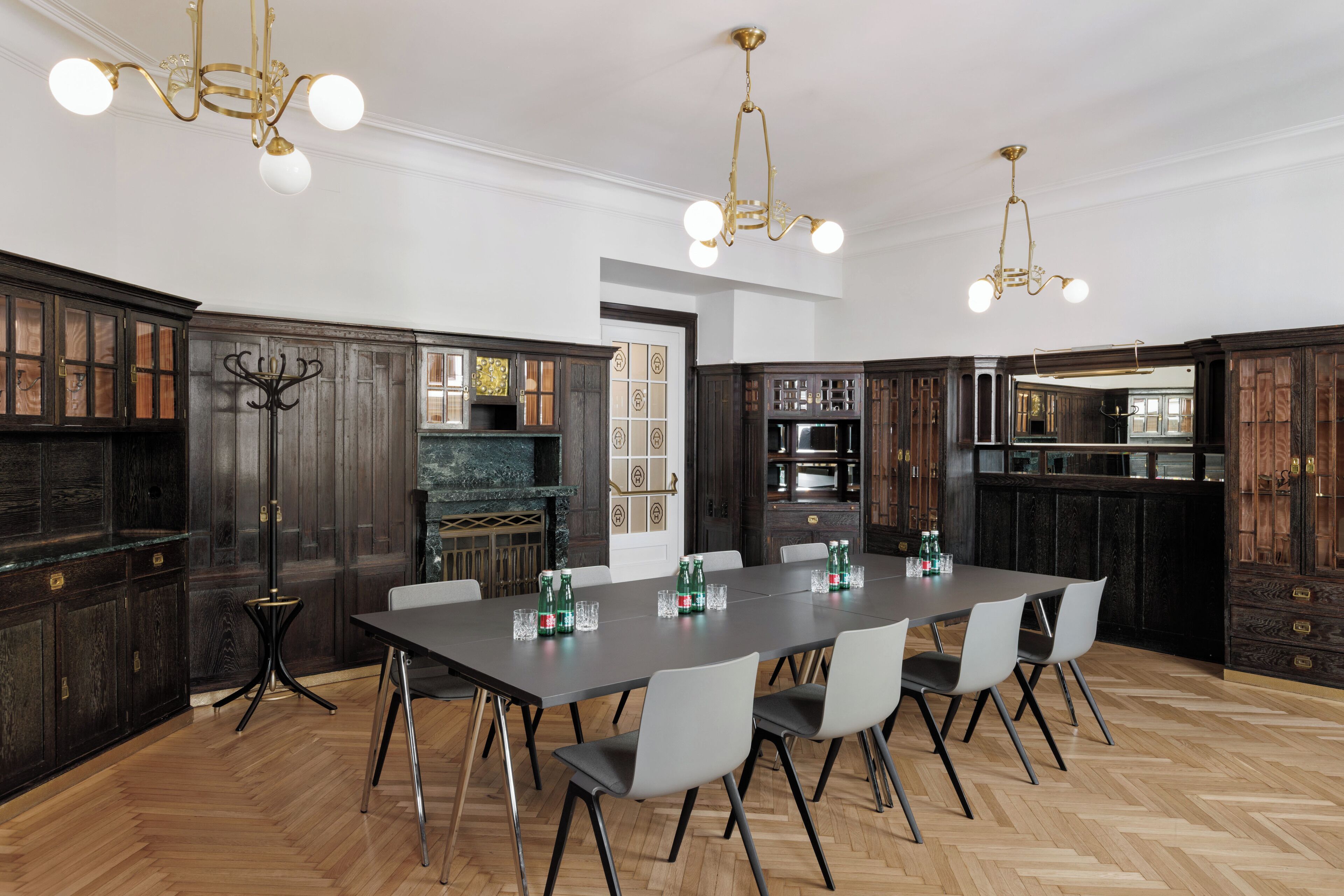 Un vaste espace dédié à la salle à manger, avec une longue table, des chaises modernes et des meubles de rangement en bois foncé.