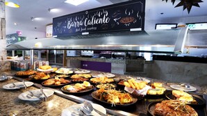 Ein Buffet mit verschiedenen Gerichten, darunter frittierte Speisen und ein großes Steak, in einem Restaurant.